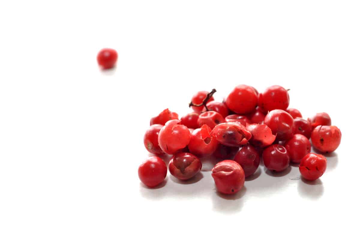 A small pile of red peppercorns on a white surf.