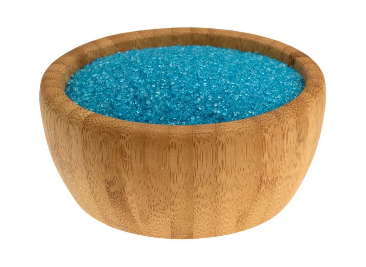 A wooden bowl full of blue sanding sugar isolated on wh.