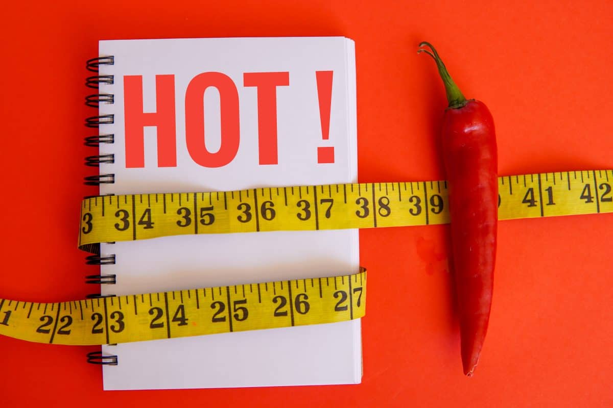 A pepper next to a notebook saying HOT, and a tape measure across the im.