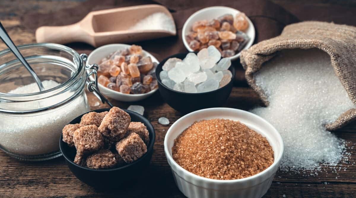 Many different types of sugar, in bowls, in a sack, spilled onto a table and more.