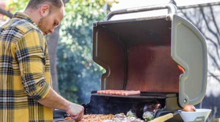 A man cooking on a charcoal grill.