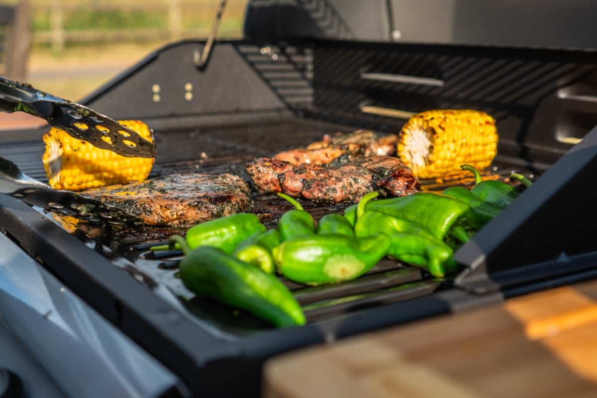 a grill full of colorful corn, meat and .