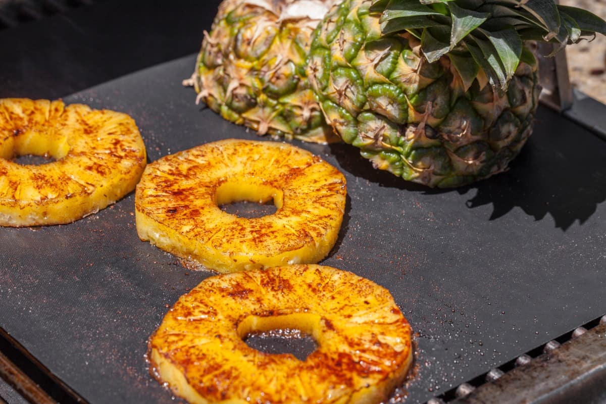 pineapple slices and a the top half, sitting on a hot grill .