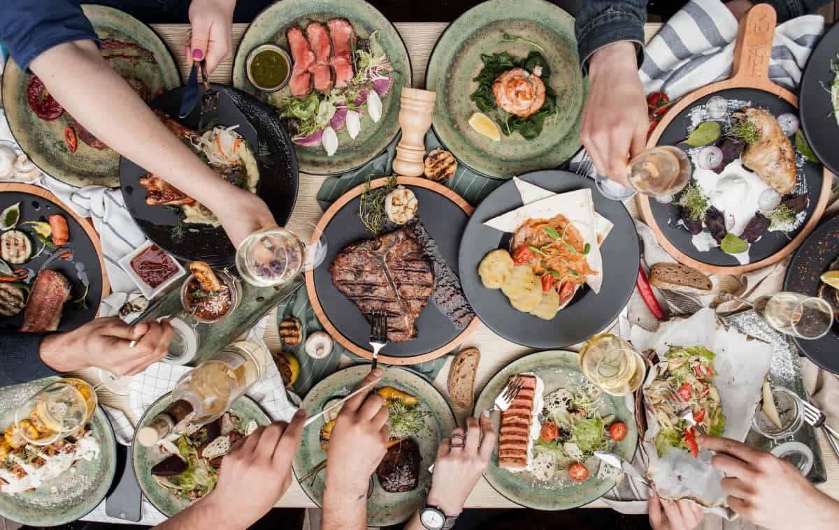 Overhead view of a table full of grilled food on pla.