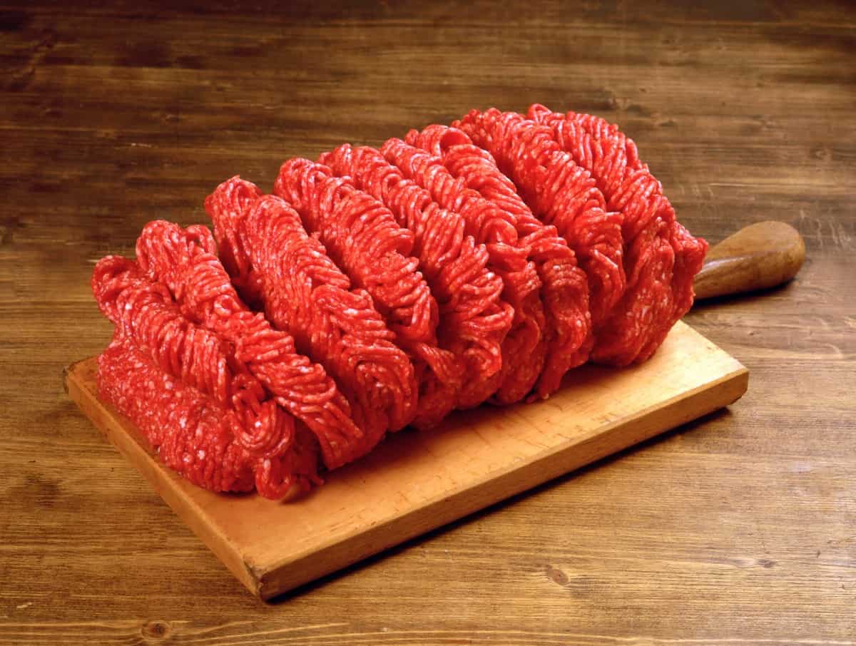 ground beef on a wooden paddle with handle