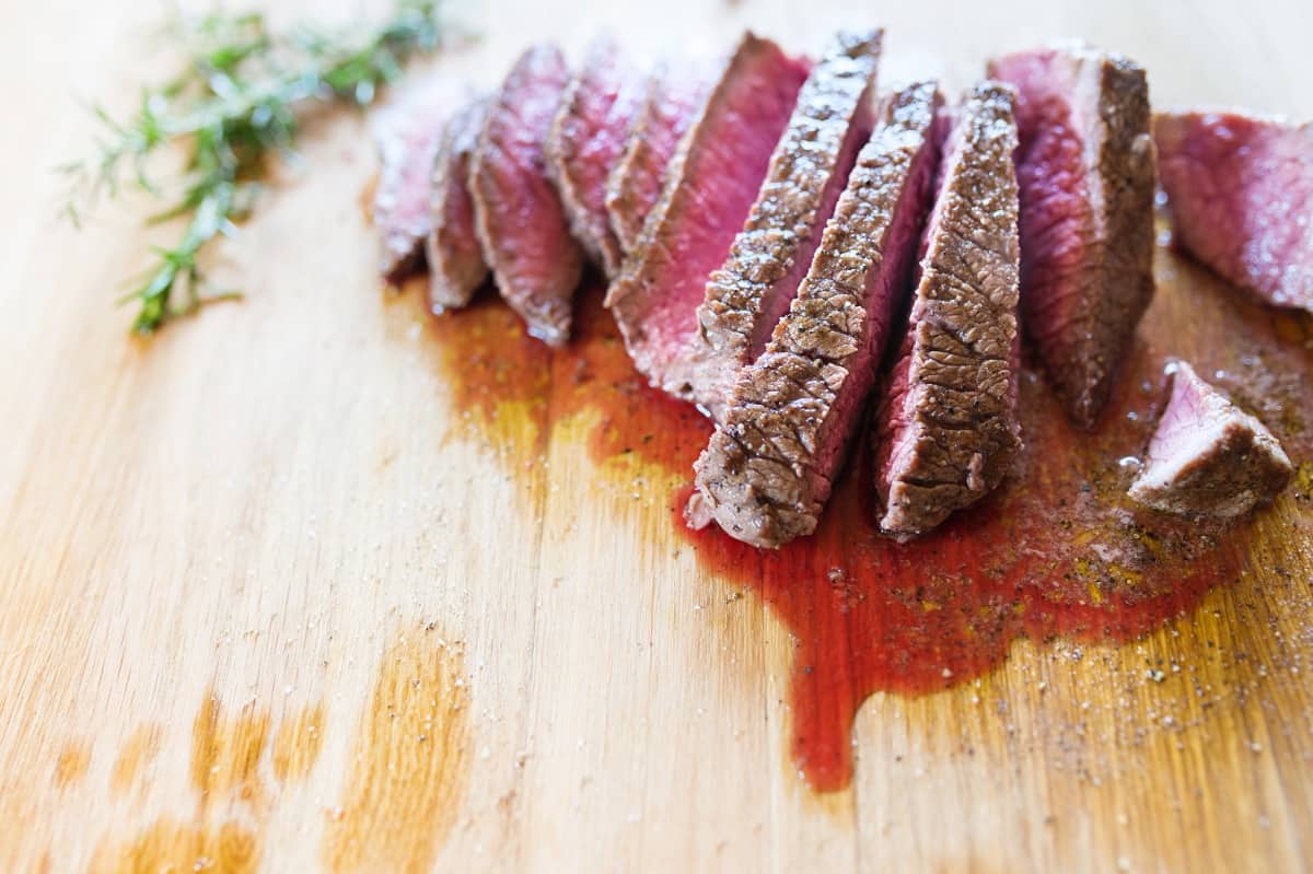 A sliced steak with juices running on cutting bo.