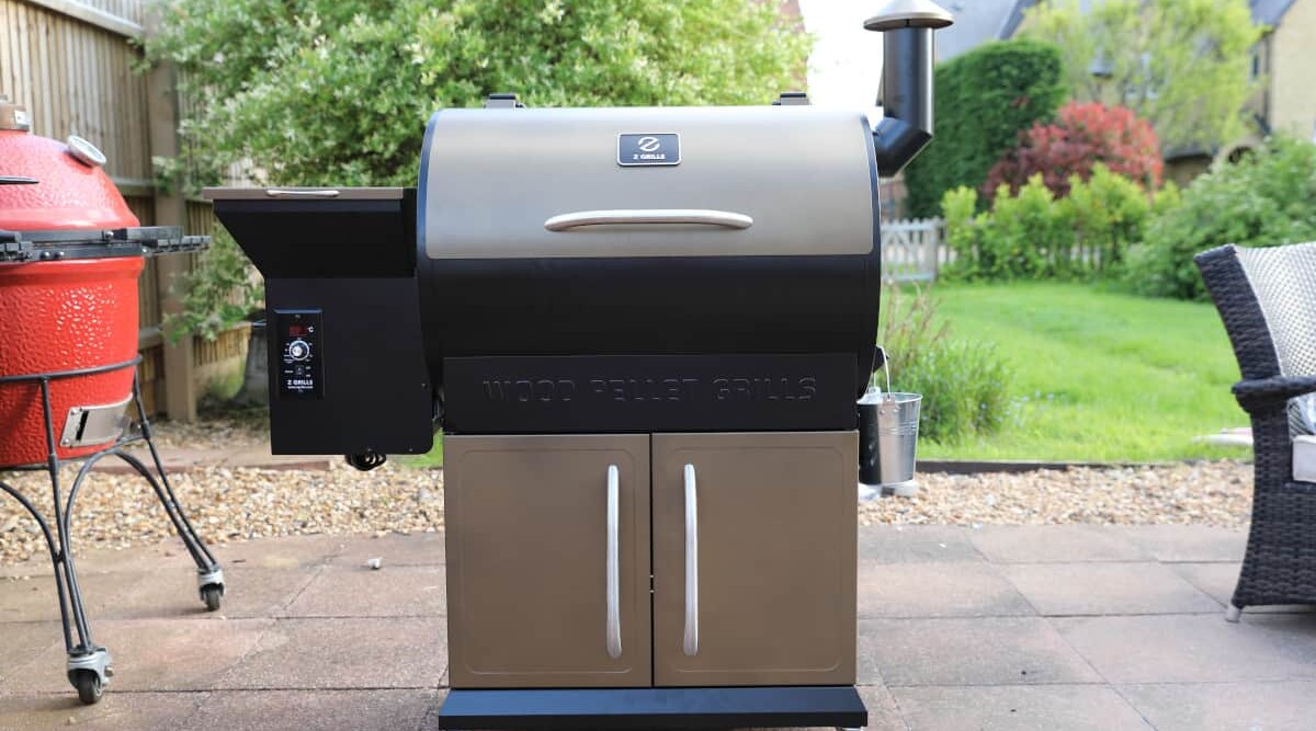 The Z Grills 700D pellet grill sitting on a patio next to a kamado grill.