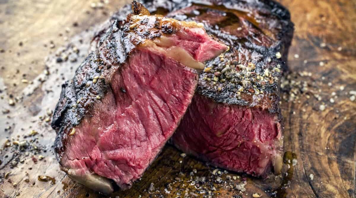 A blu rare, grilled wagyu ribeye steak cut in half.