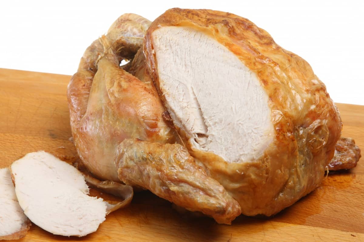 A roast chicken with a couple of slices carved away from it's breast