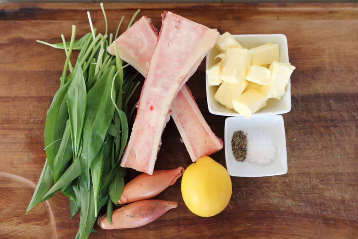  Wild garlic and bone marrow butter ingredients on a wooden cutting bo.