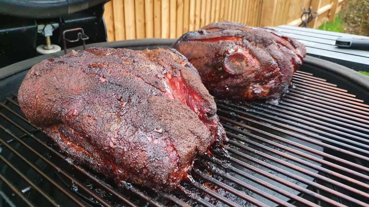 Angled view of two smoked pork butts on a kamado gr.