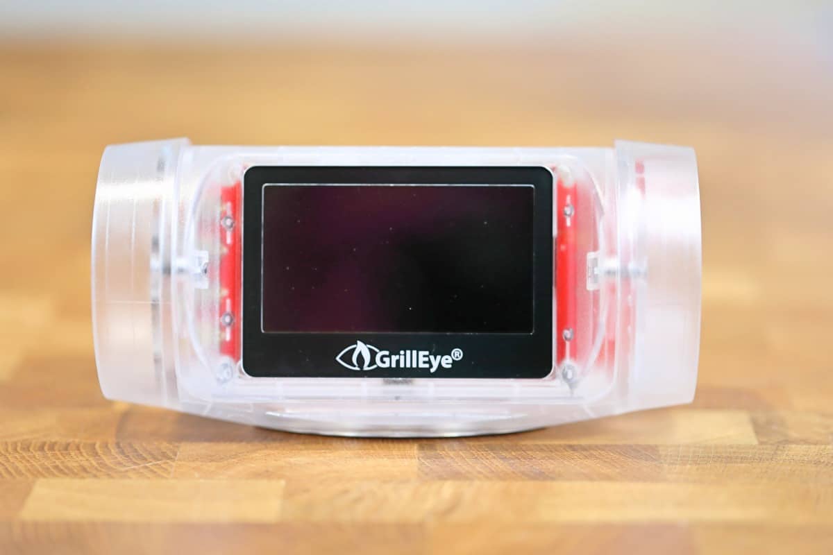 Grilleye max thermometer, no probes and turned off, sitting on a wooden ta.