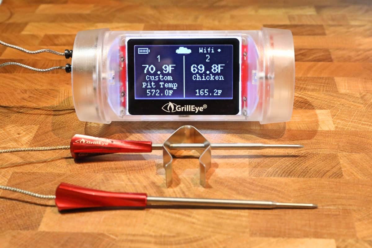 Grilleye Max thermometer, with two probes attached and turned on, sitting on a wooden chopping block.