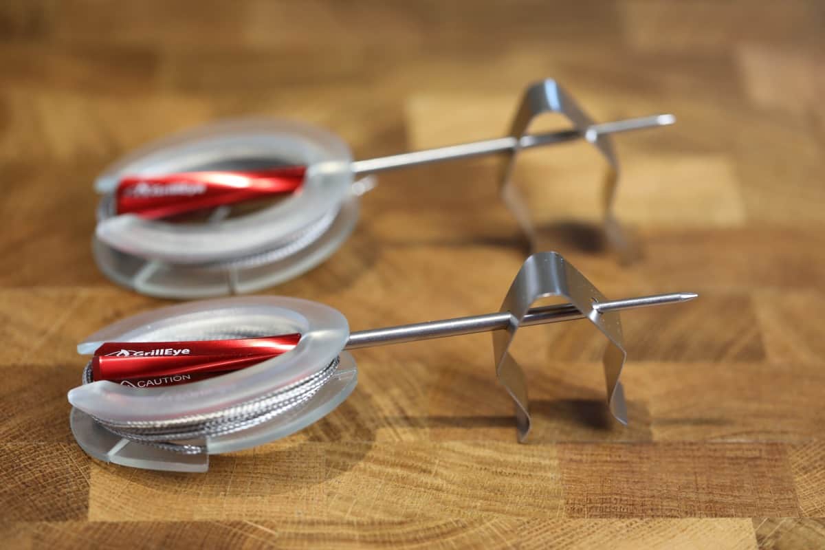 Two Grilleye max probes in their cable tidies, sitting on a wooden table.