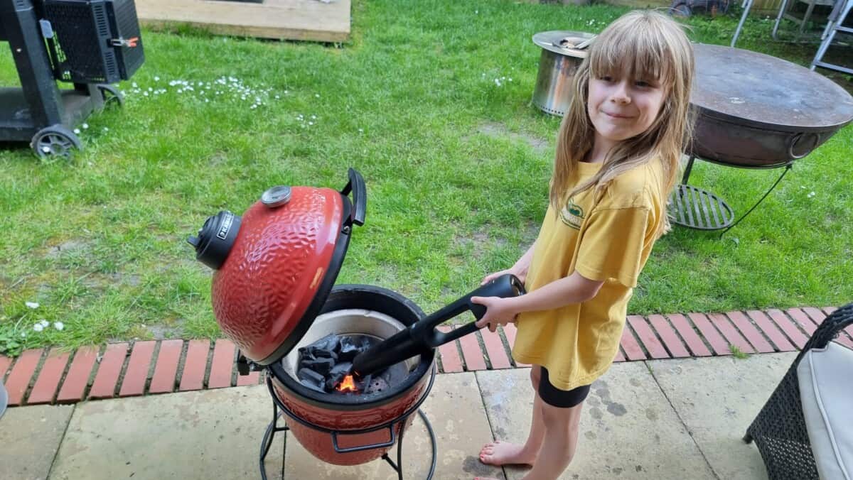 A young girl with a Looftlighter, lighting a Kamado Joe Jr. grill.