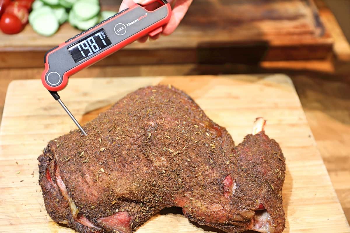 Instant read thermometer being used to take the internal temperature of a lamb should.