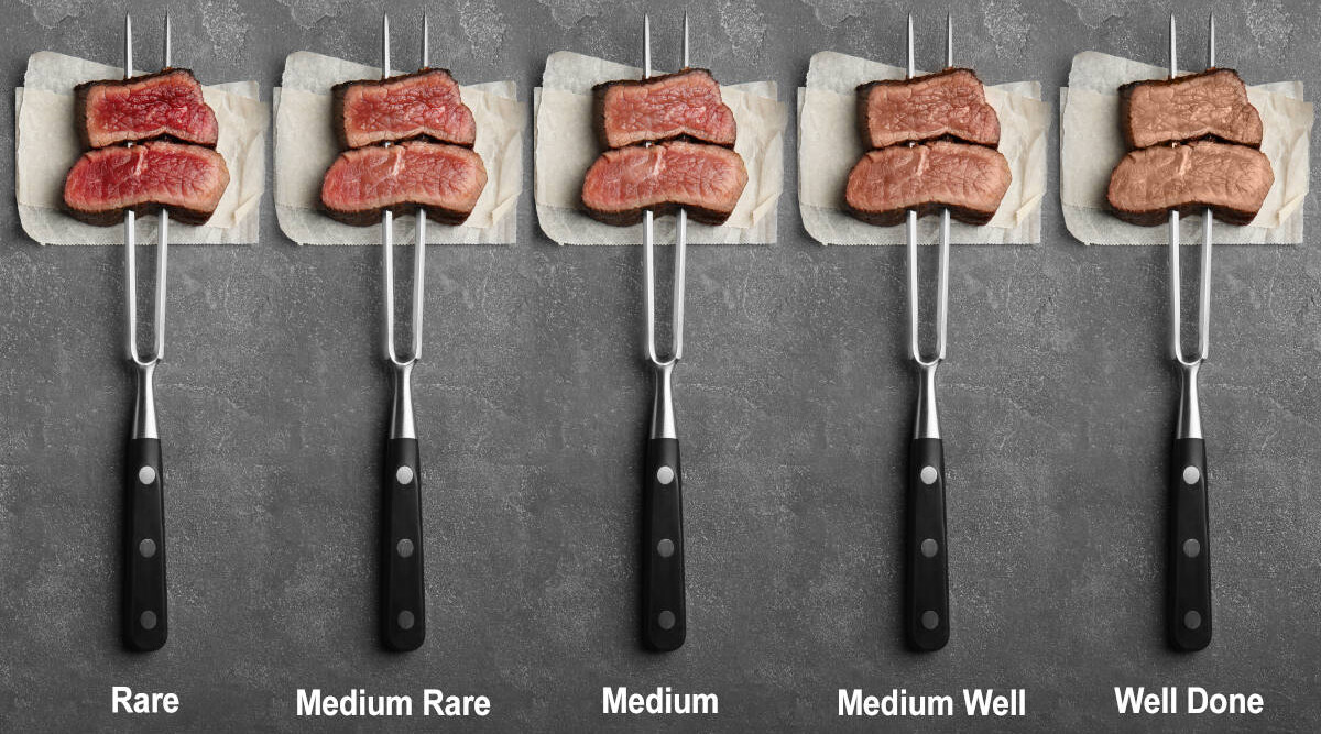 Steaks cooked from rare to well done, on forks on a dark background.