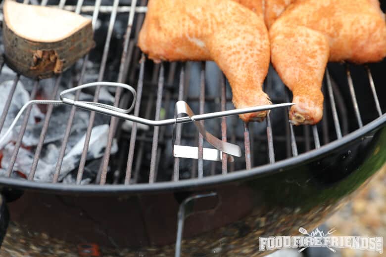 Thermopro tp20 pit probe in a kettle grill, next to a spatchcock chicken.