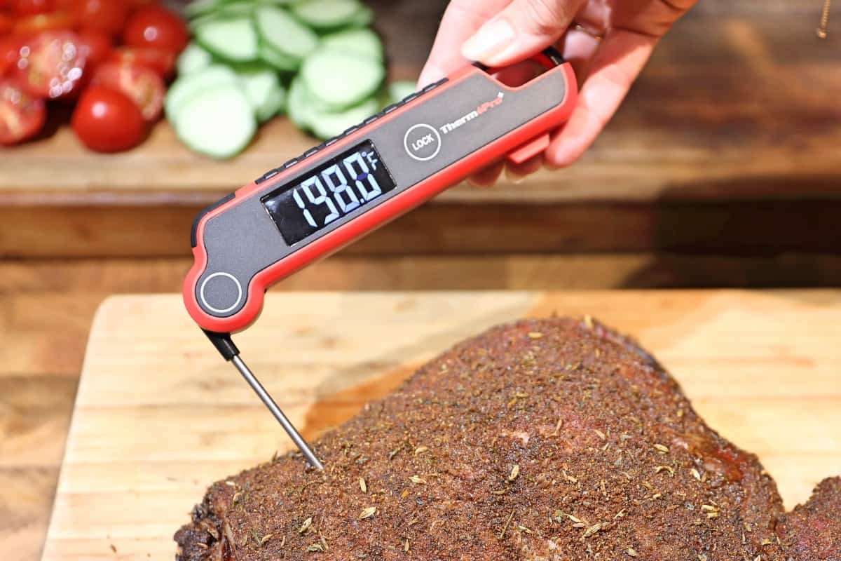 Thermopro tp620 taking the temperature of a lamb leg, held by a mans h.