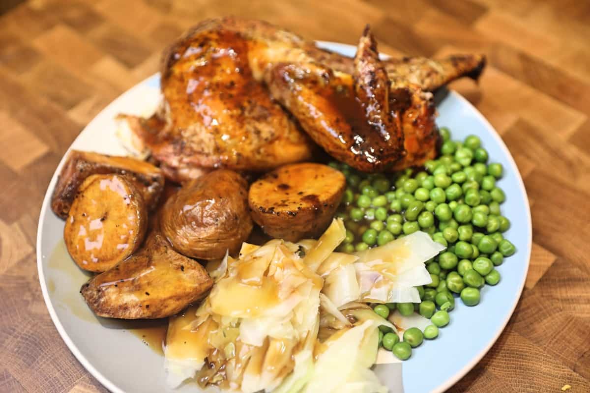 Overhead shot of a chicken dinner, with chicken pieces, peas, roasted potatoes, and cabbage
