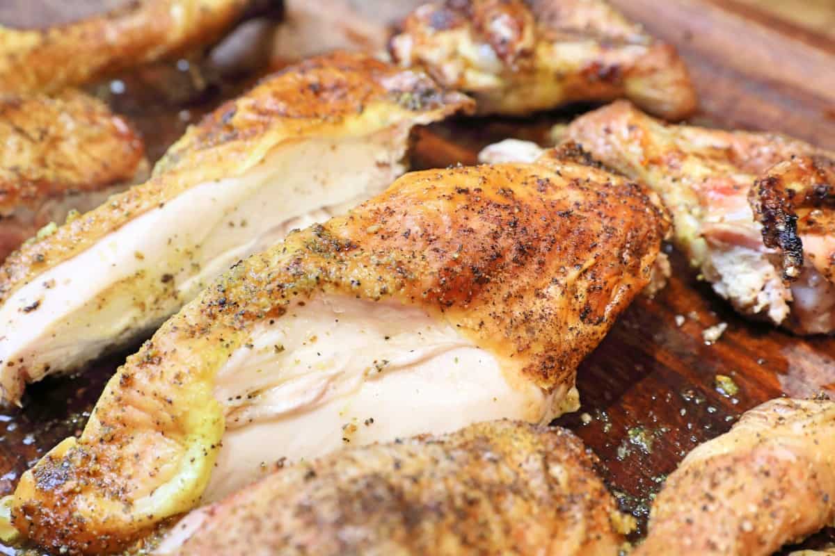Close up of grilled chicken pieces on a cutting board.