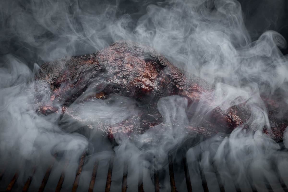 Close up of a beef brisket surrounded by swirling sm.