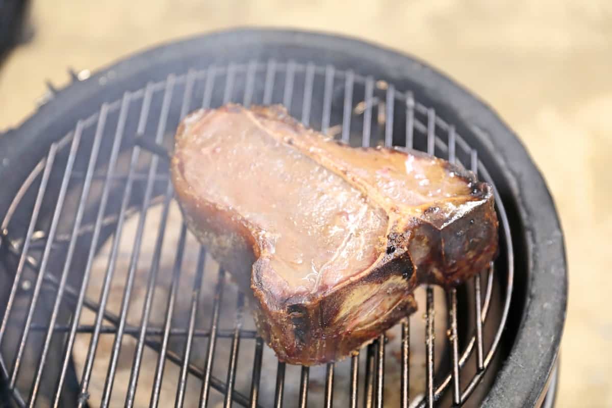 A partially cooked, smoked steak on a kamado Joe Jr gra.