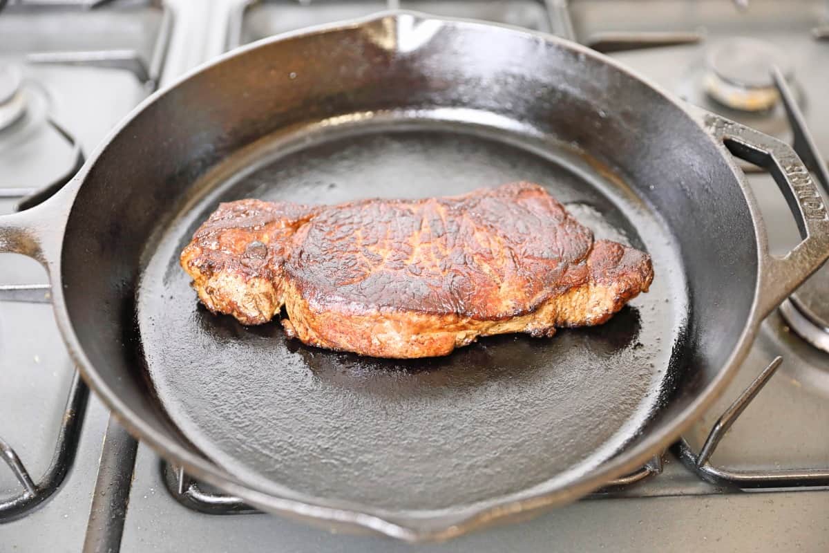 A steak being reheated on a hob, in a cast iron .