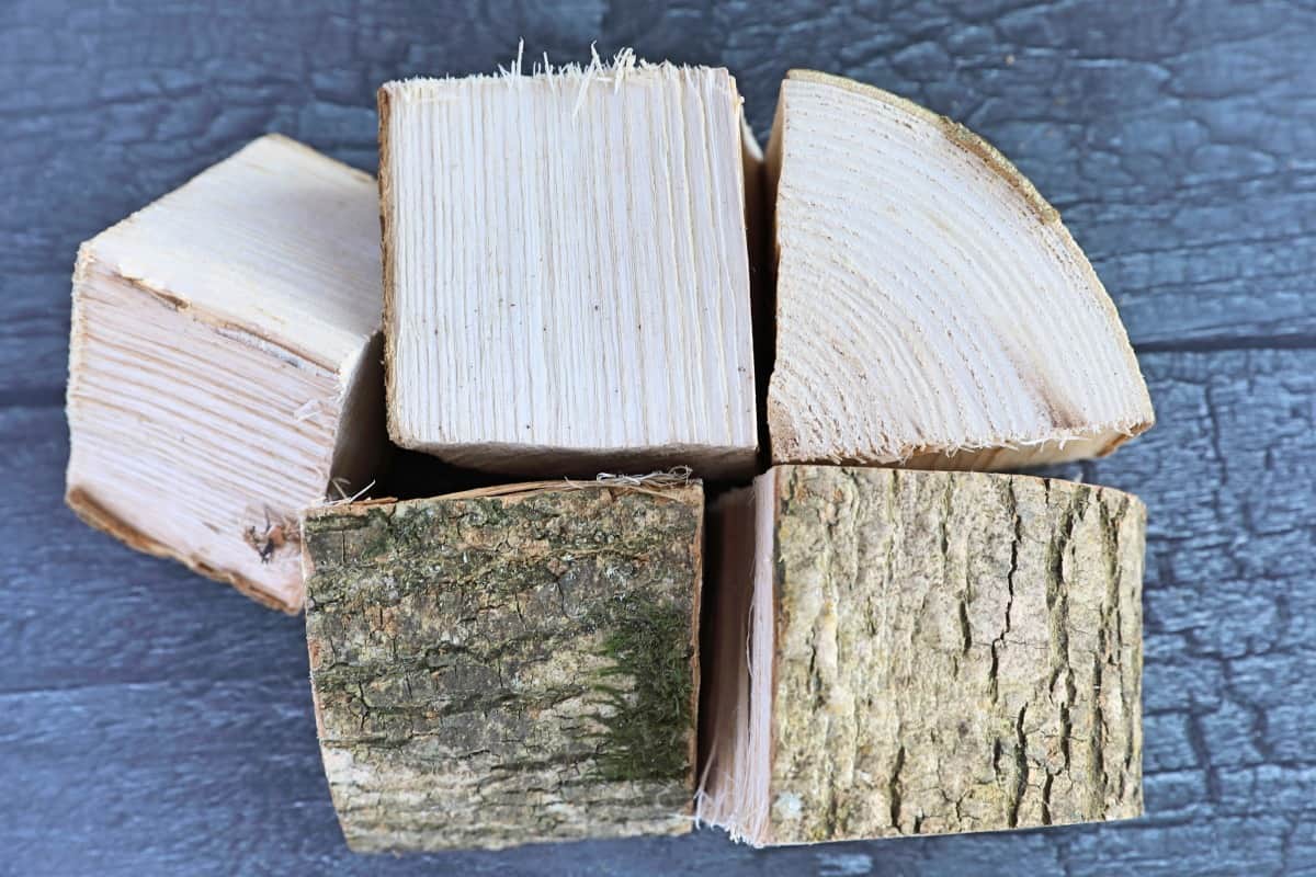 Five pieces of ash smoking chunks on a dark wooden table.