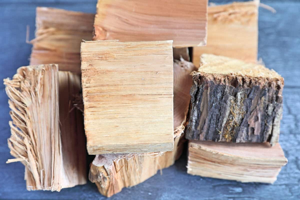 A pile of hickory wood chunks on a dark wooden tab.