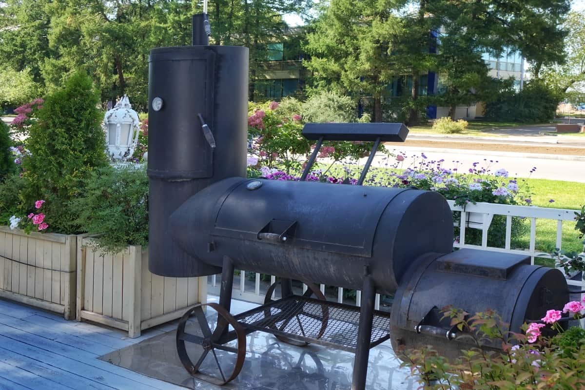 A an offset style bbq smoker in a backy.