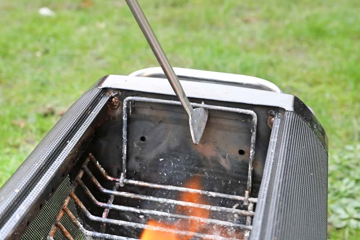 Biolite poker being used to raise or lower the fire basket