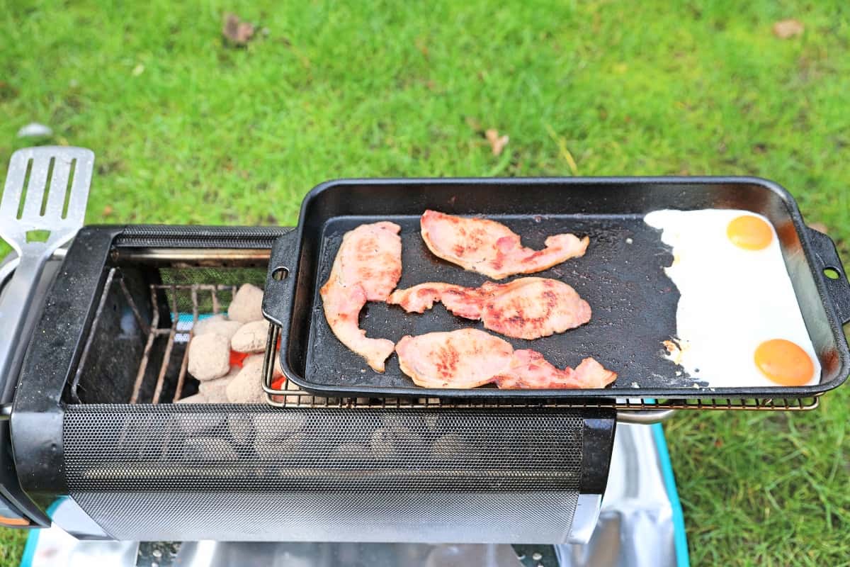 bacon and eggs cooking on the biolite firepit+ griddle access.