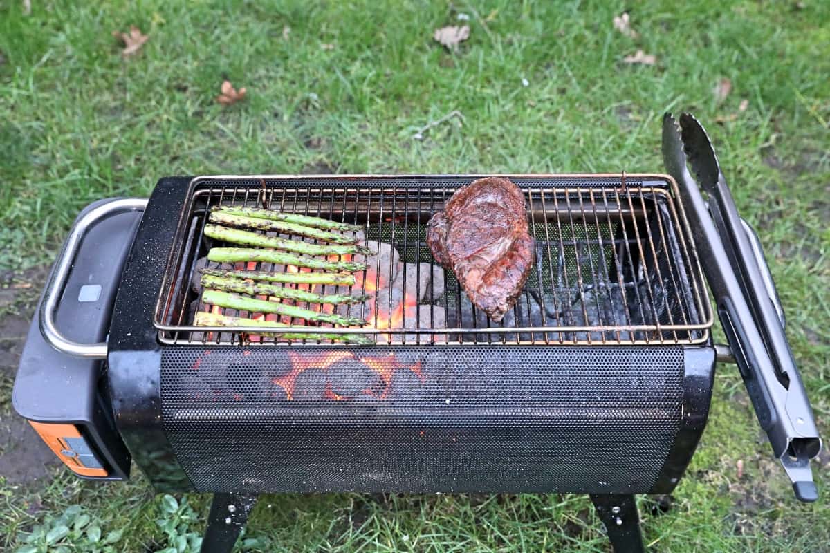 Steak and asparagus being grilled on a firepit.
