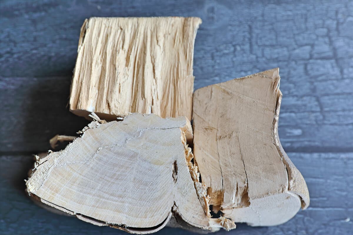 Three chunks of orange wood on a dark table, showing us different angles of the woods grain.