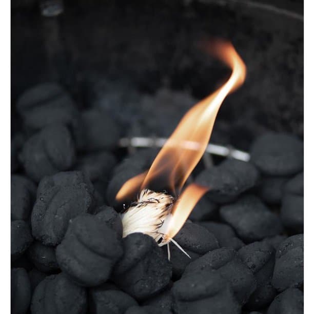 A pile of Royal Oak charcoal with a wood wool firestarter lit in the center