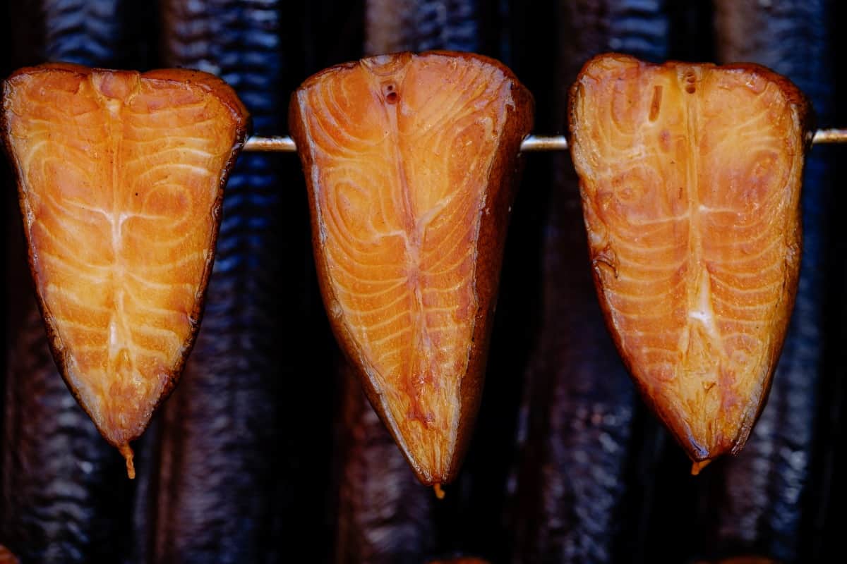 Three fish fillets hanging vertically in a smoker.