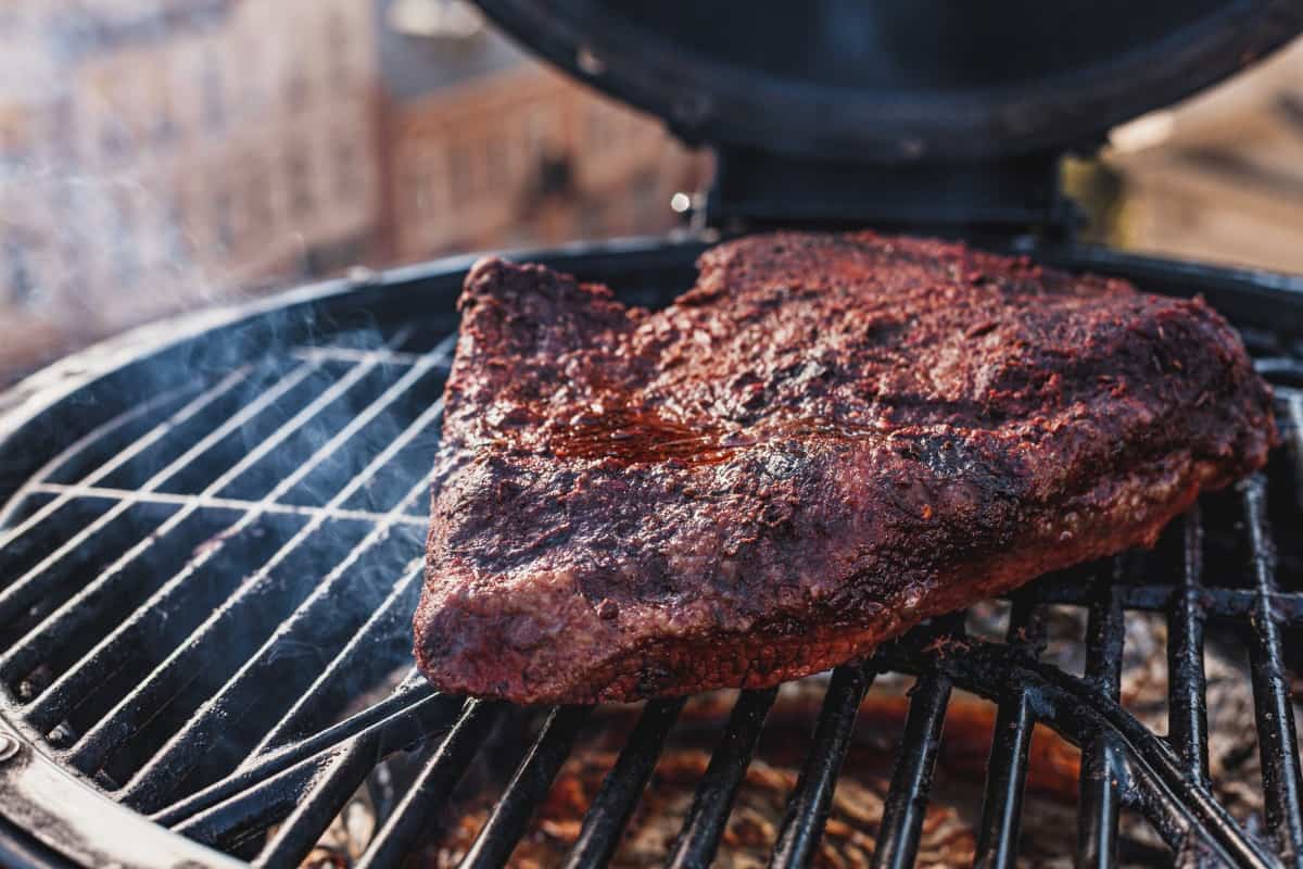 Close up of a brisket in a round smoker, being slowly smo.