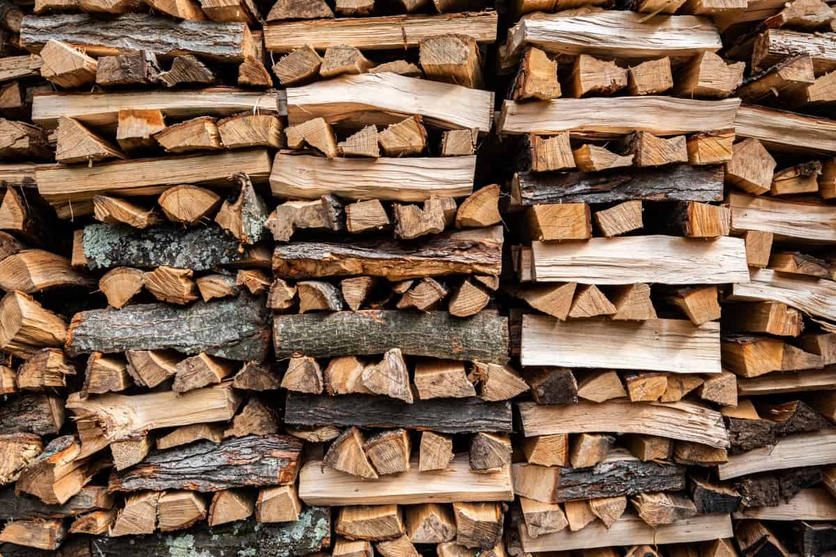 Smoking wood logs piled up high, in alternating perpendicular laye.