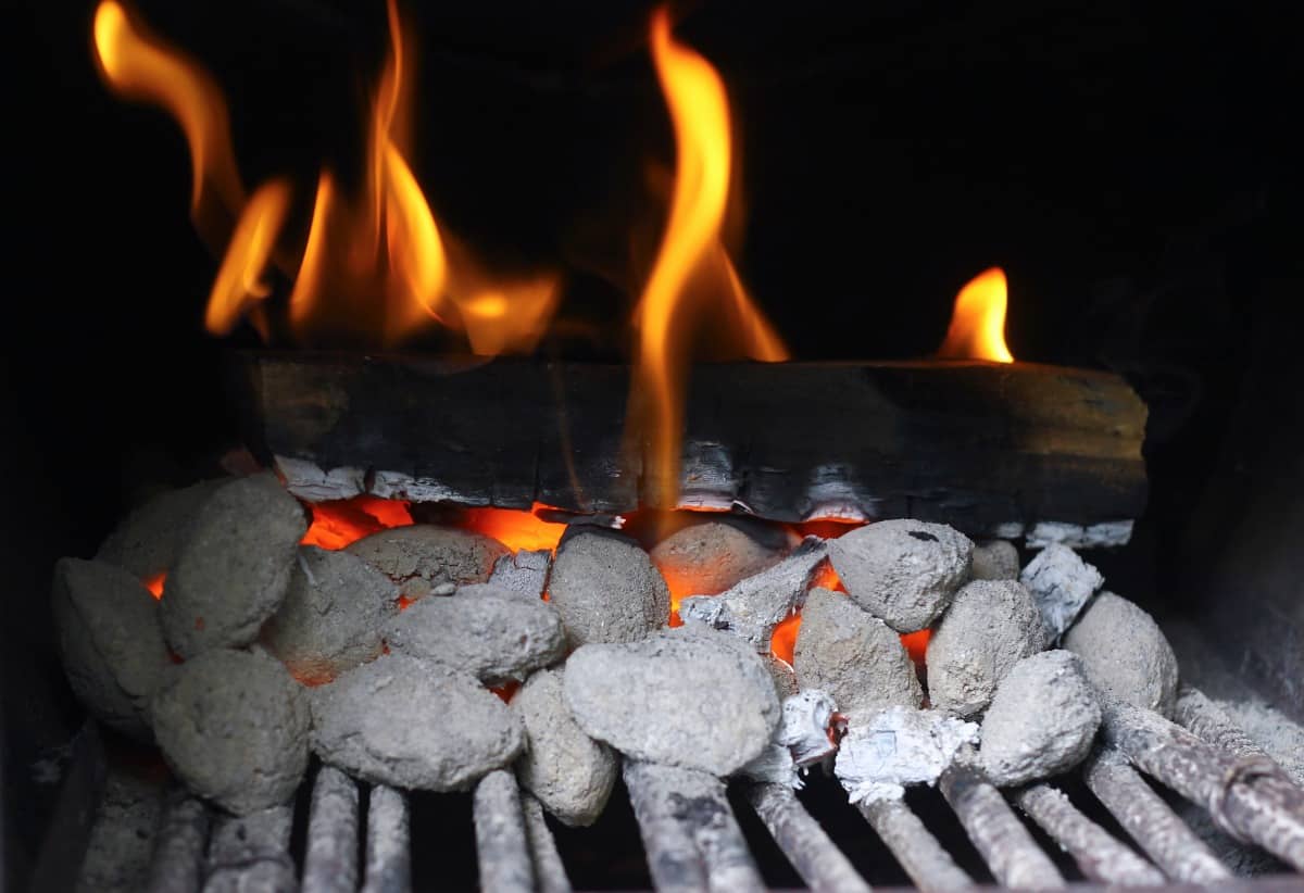 Hardwood smoking log on top of charcoal in an offset smo.