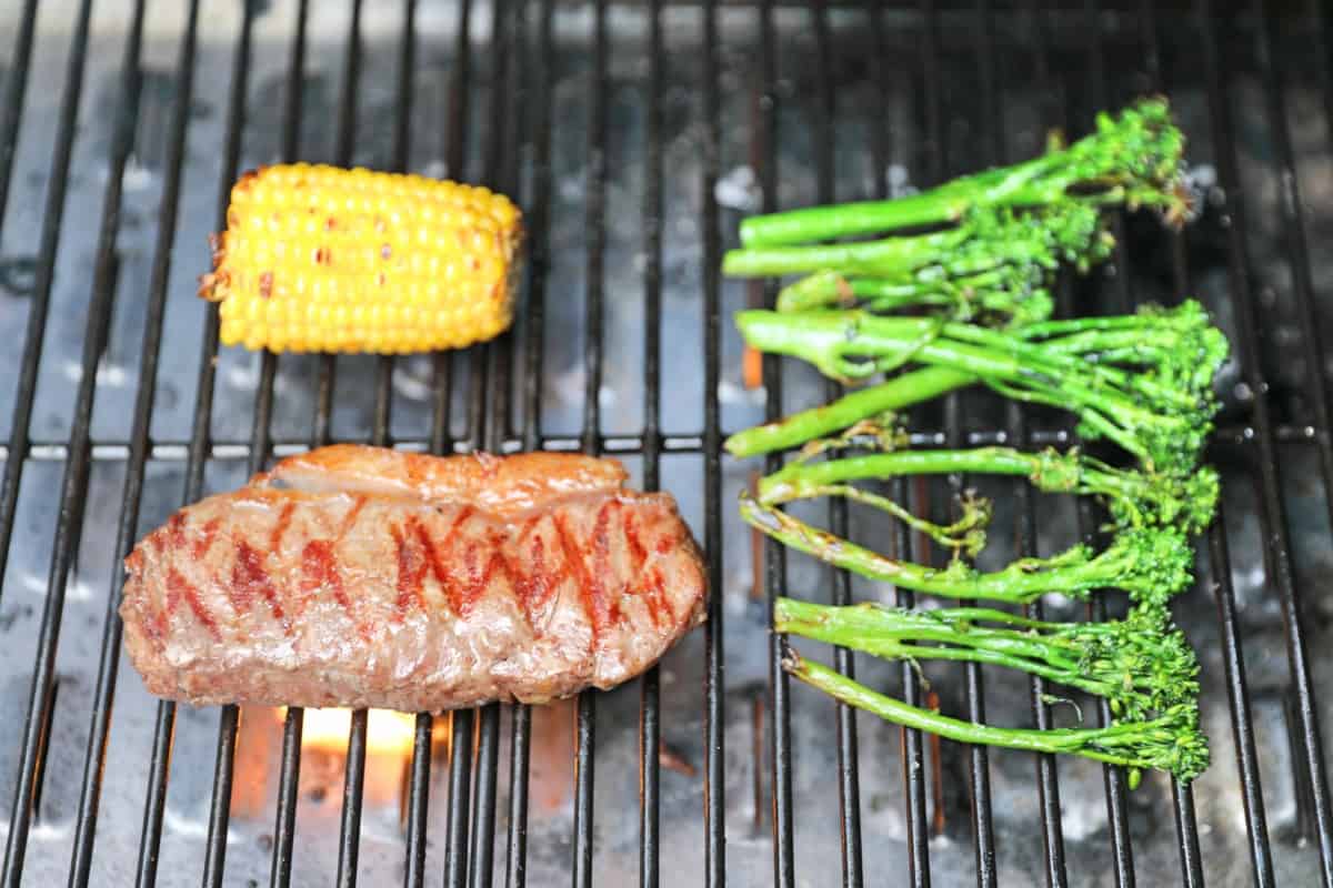 Steak, corn and tender stem brocoli being grilled in a Camp Chef Woodwind pellet grill.