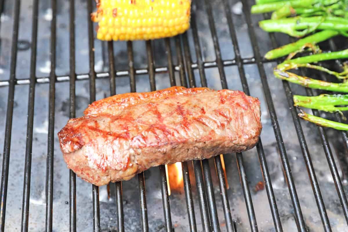 Steak, corn and tender stem brocoli being grilled in a Camp Chef Woodwind pellet grill.