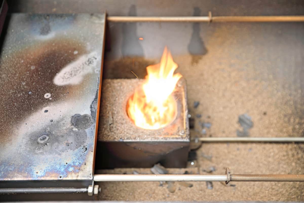 Flames rising from the uncovered fire pot in a Camp Chef Woodwind Wi-Fi 36 pellet smoker.