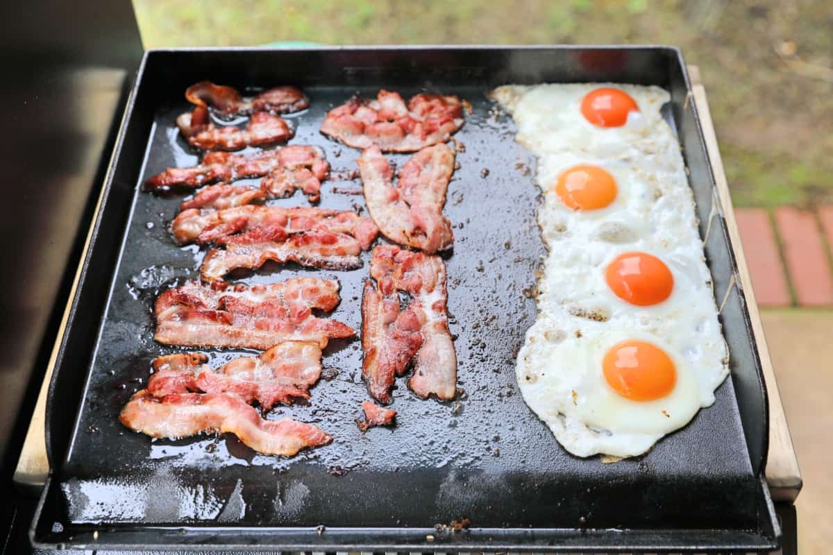 eggs and bacon cooking on the Camp Chef Woodwind Sidekick griddle attachm.