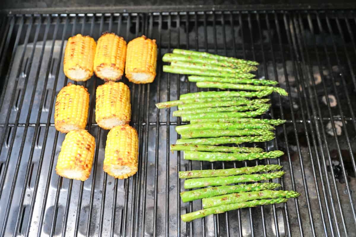 Corn and asparagus grilling in the main chamber of a Camp Chef Woodwind Wi-Fi 36.