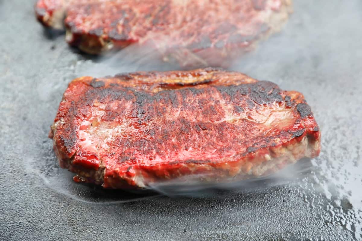 A steak searing on a cast iron griddle.