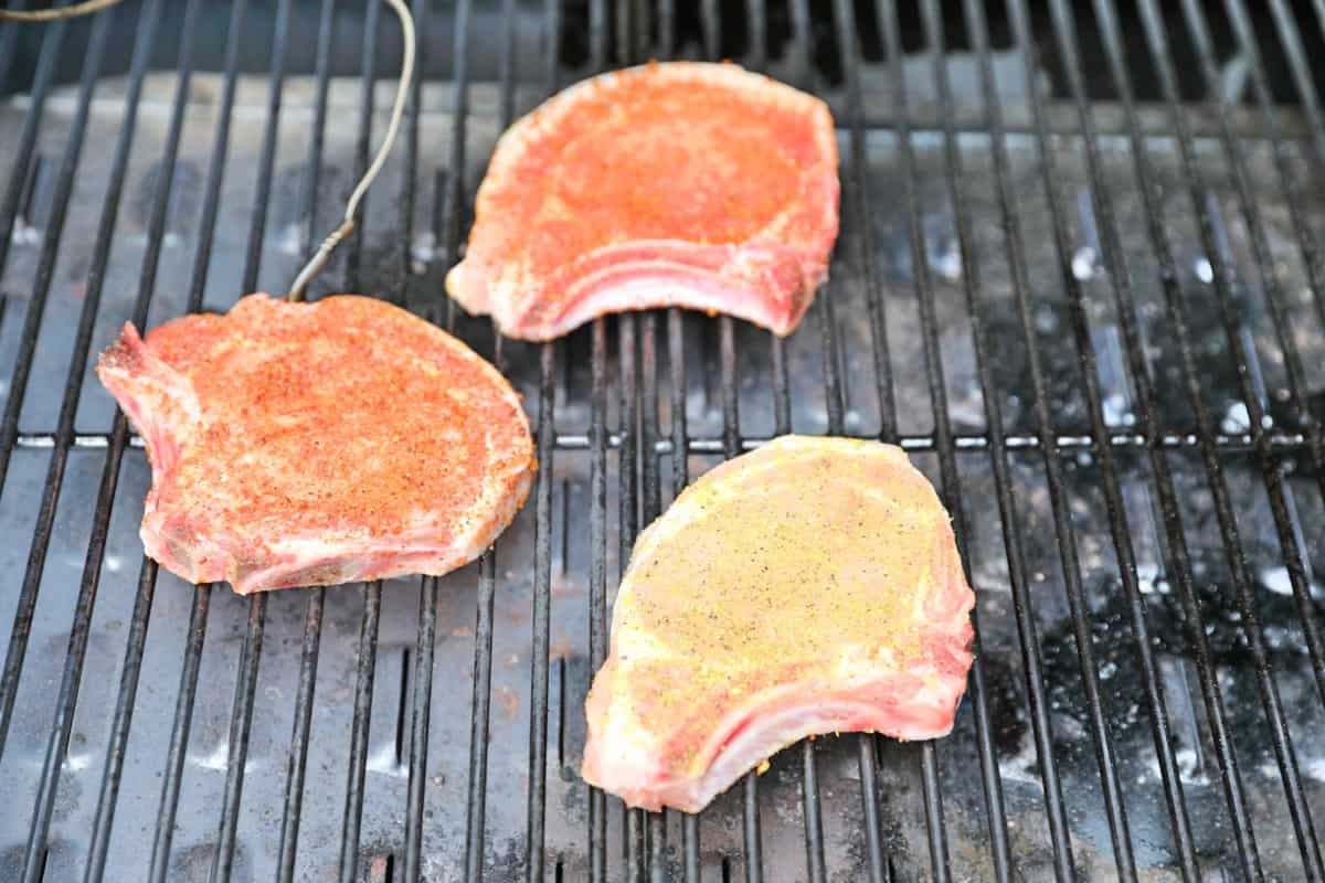 Three prok chops being seared in a pellet grill.