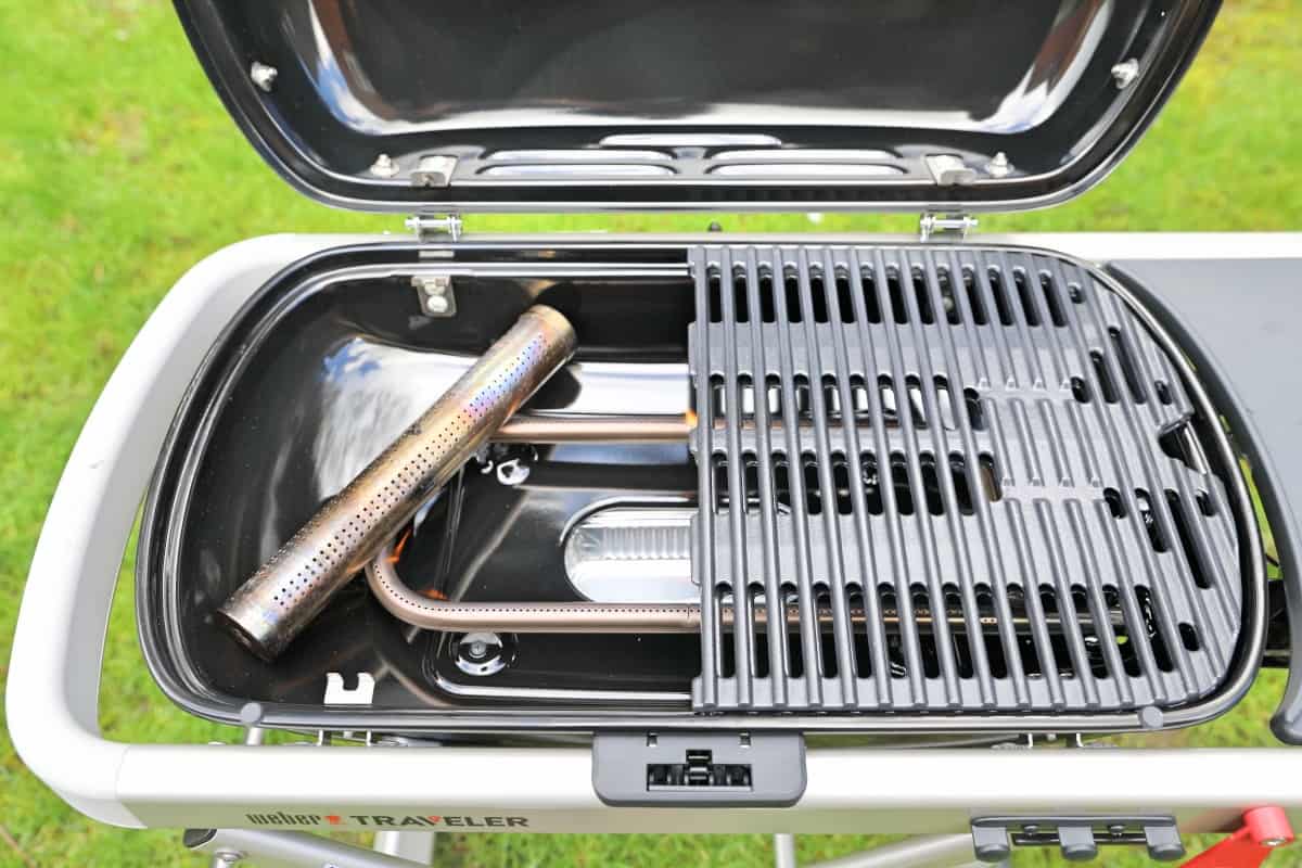 A smoking tube inside the Weber Traveler gas grill, with a single grate removed