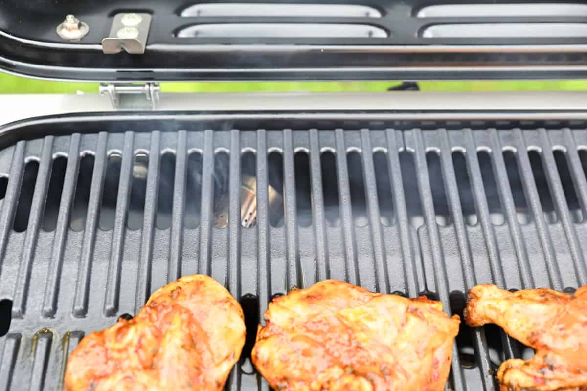 Close up of smoke being generated on the Weber Traveler gas grill via a smoke tube between burner and grates.