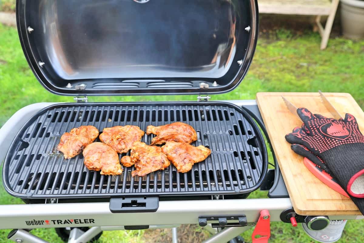 Chicken pieces being smoked inside the Weber Traveler gas grill.